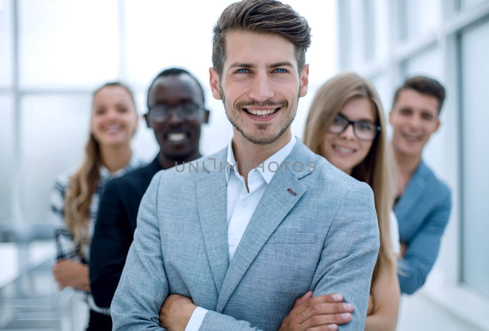 Young man with arms folded and friends behind him against a white background