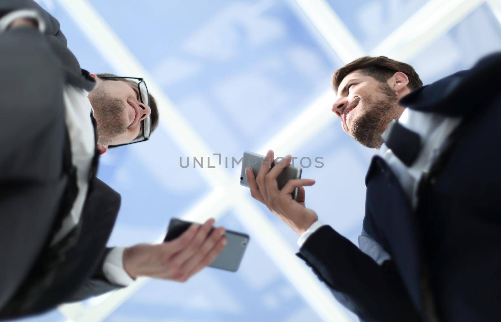 Two businesspeople standing on balcony of downtown office buildi by asdf