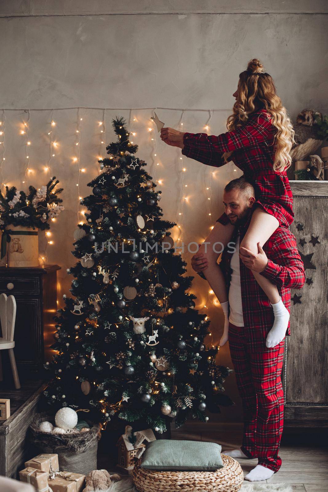 Couple decorating xmas tree at home. by StudioLucky