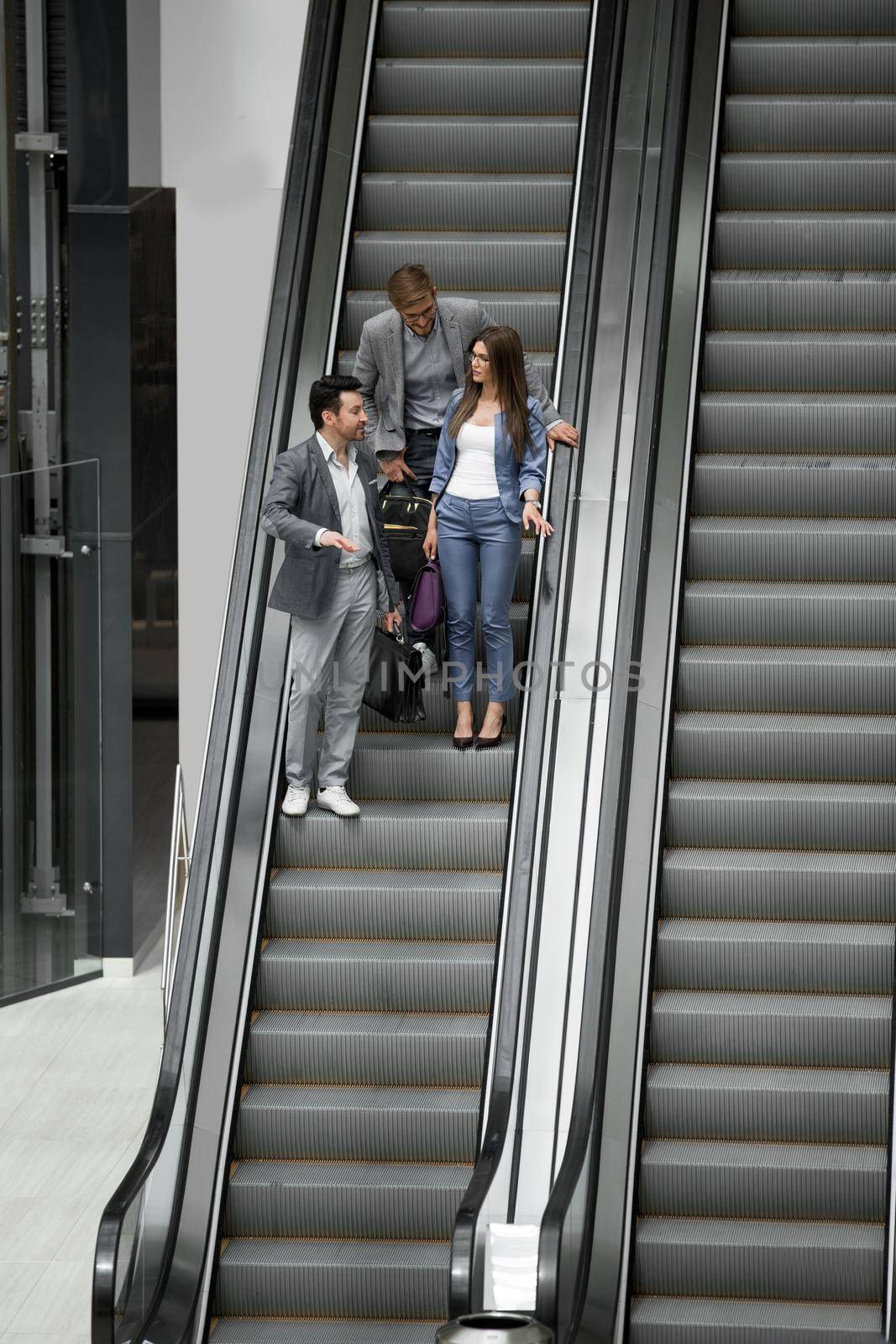 business people standing on the escalator by asdf