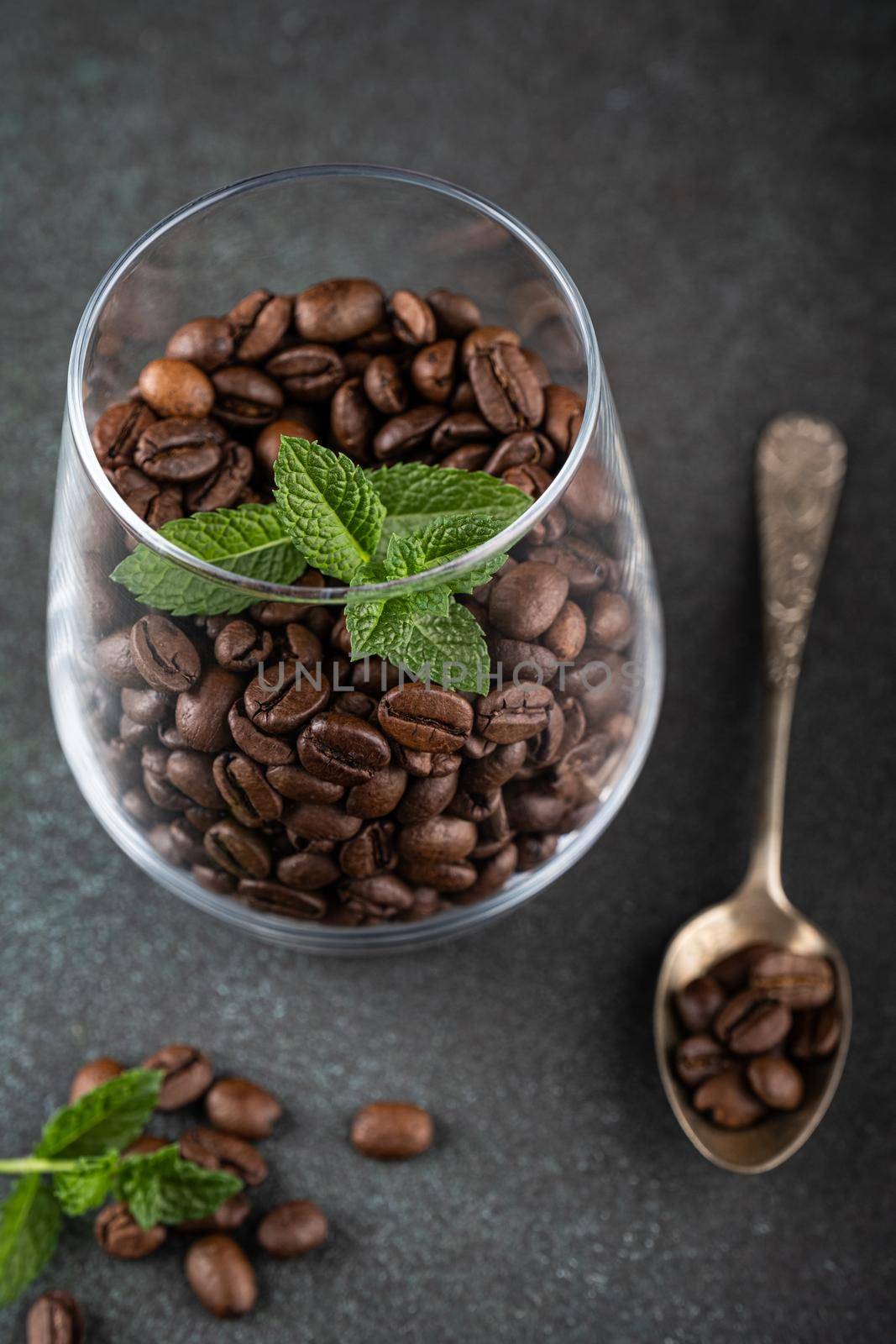 Coffee beans in glas with mint leaves on green background