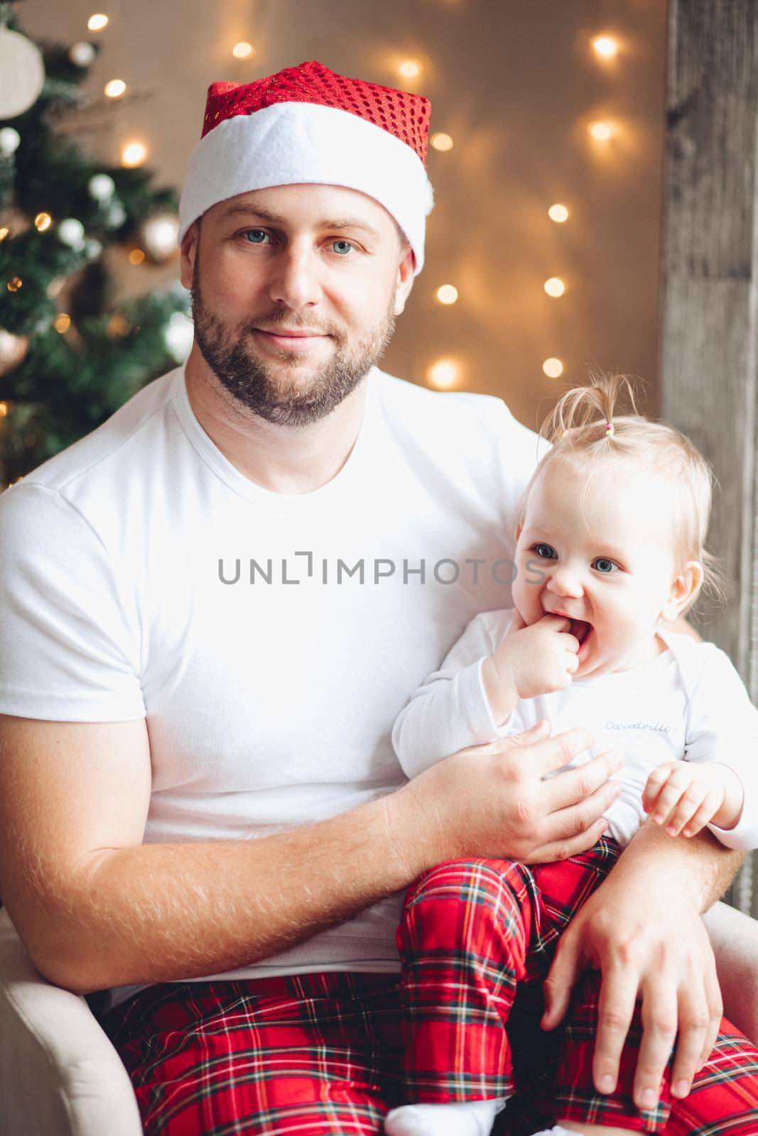 Handsome young dad hold a baby on his knees in christmas atmosphere by StudioLucky