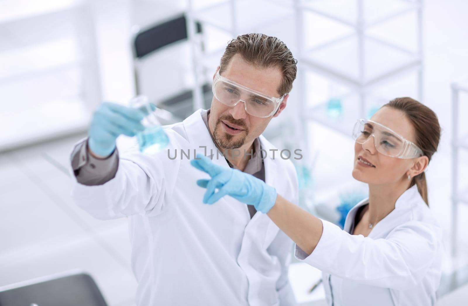 scientist and assistant look at the liquid in the flask.photo with copy space