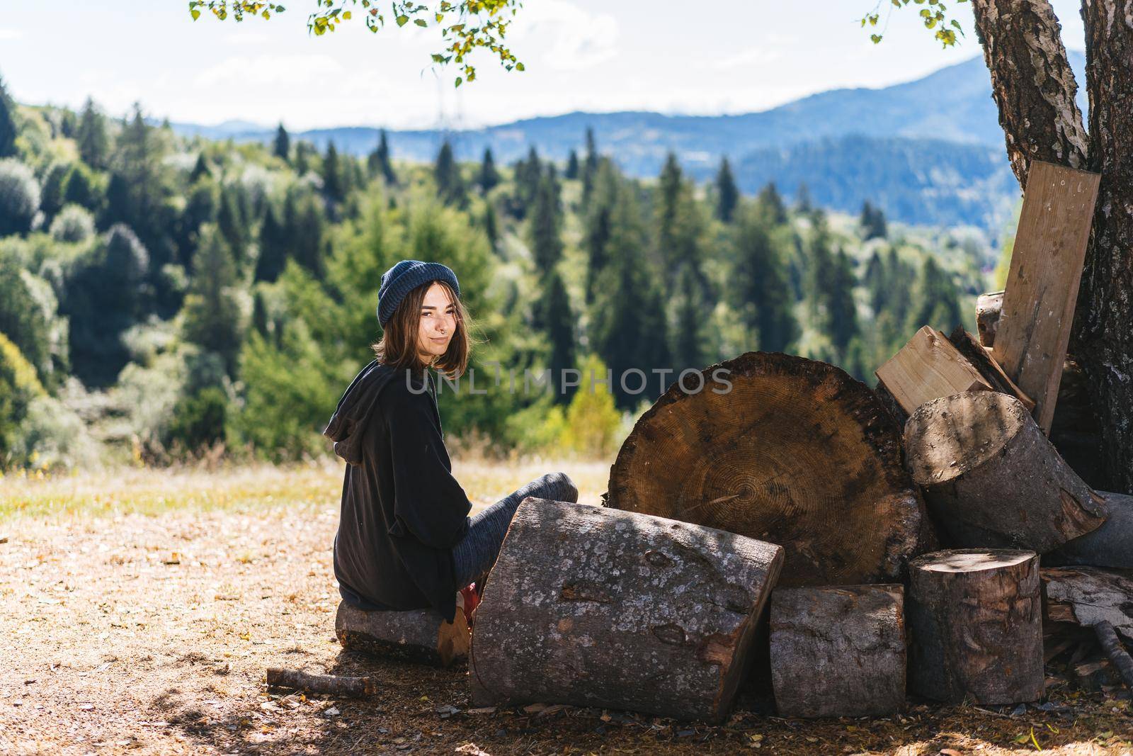 Woman next to logs of cut wood