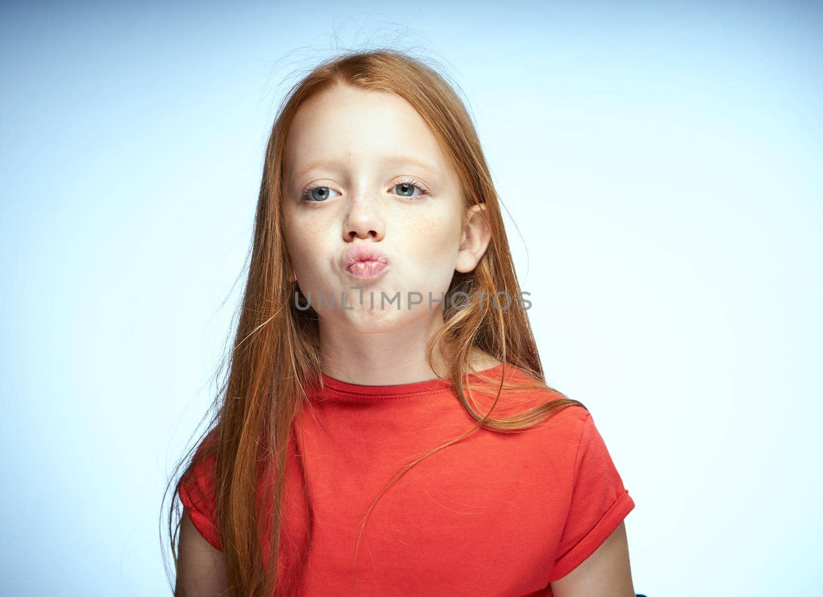 red-haired girl in a red t-shirt posing childhood. High quality photo