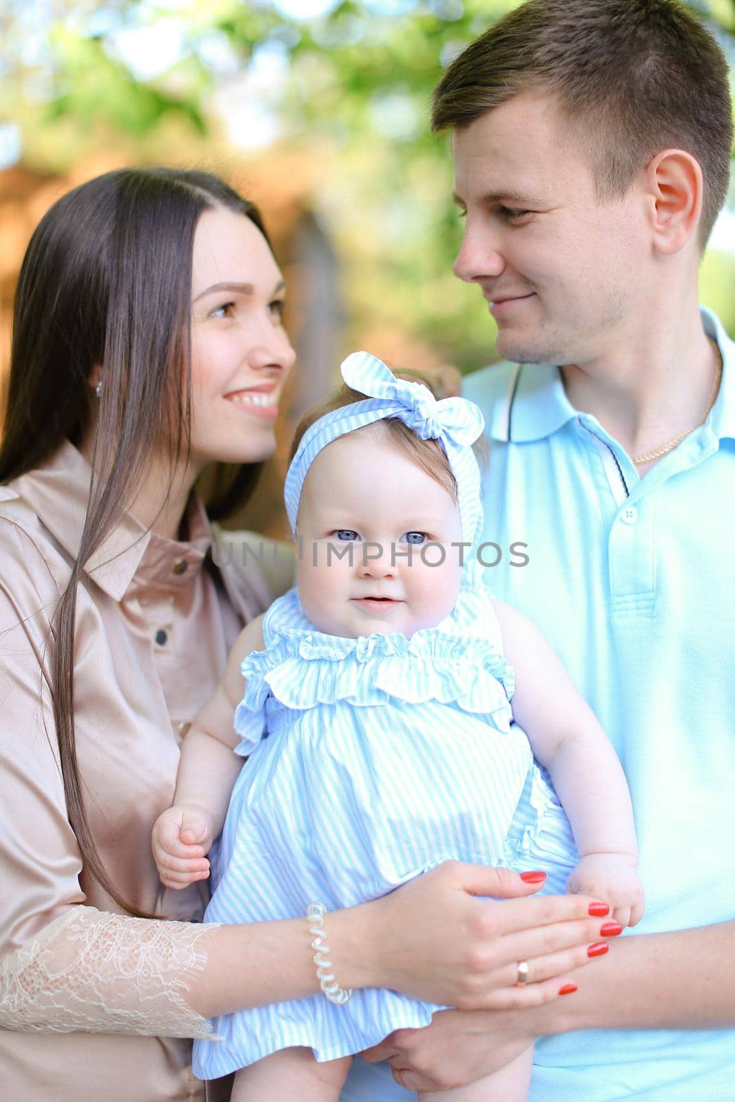 Young mother and father holding little female baby. Concept of parenthood and child.