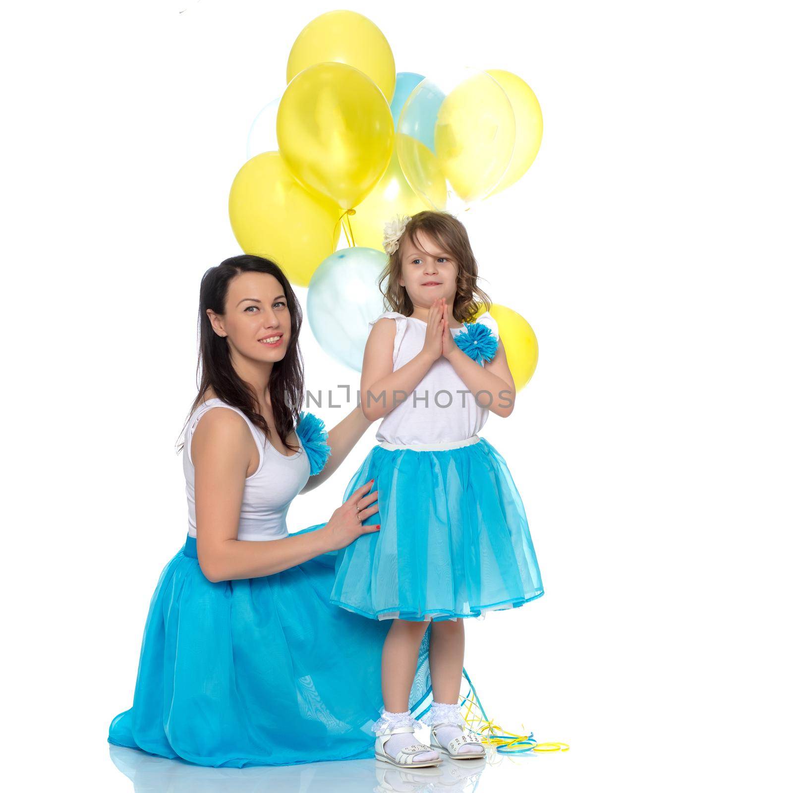 Beautiful mother and daughter in long blue skirts, along with balloons.Daughter happily folded their hands on the chest.Isolated on white background.
