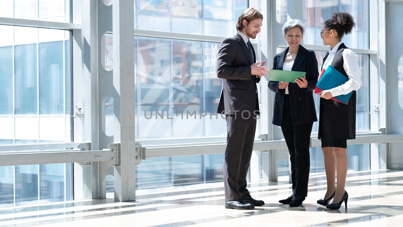 Business people talking about documents in office lobby of modern building