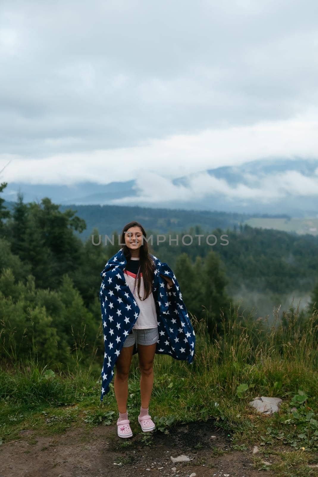 Woman standing on top of a hill, against the background of a valley in the fog