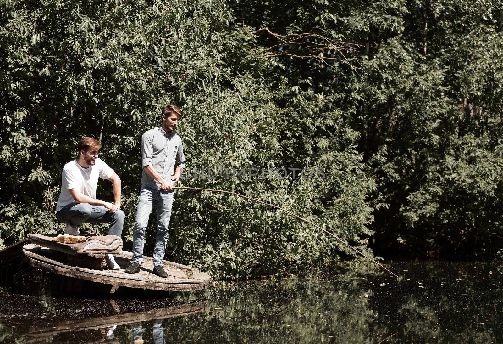 two friends are fishing on the lake in the early morning . lifestyle
