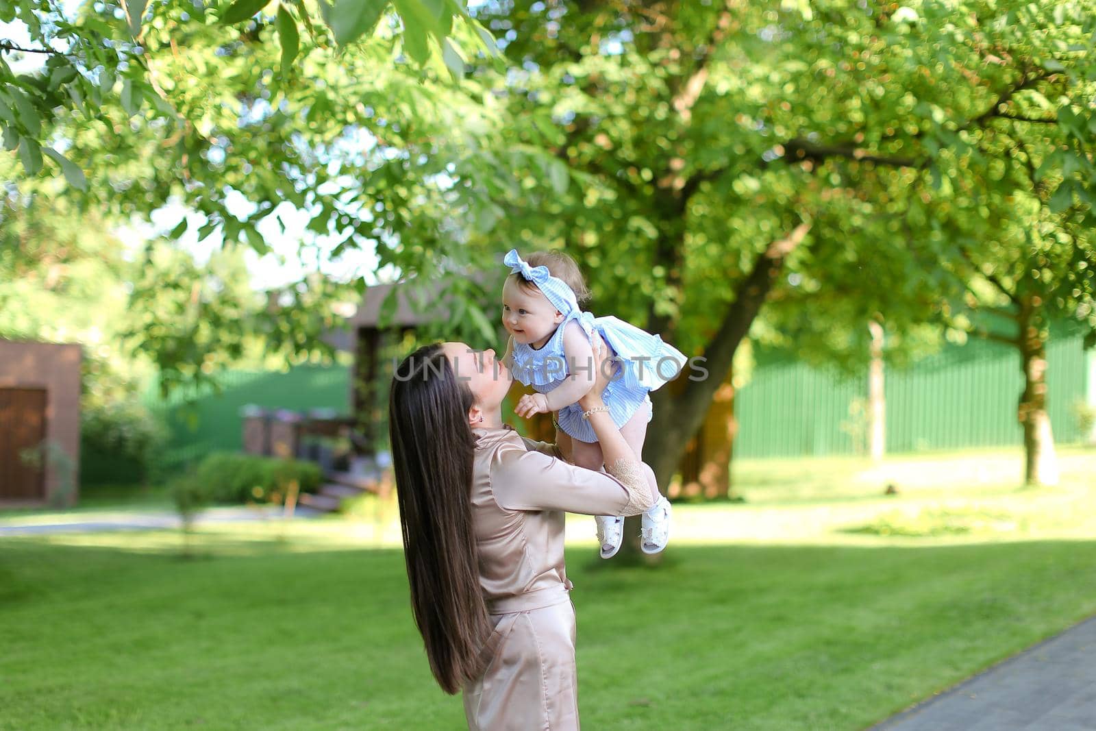 Young happy mother holding little female baby in garden. by sisterspro