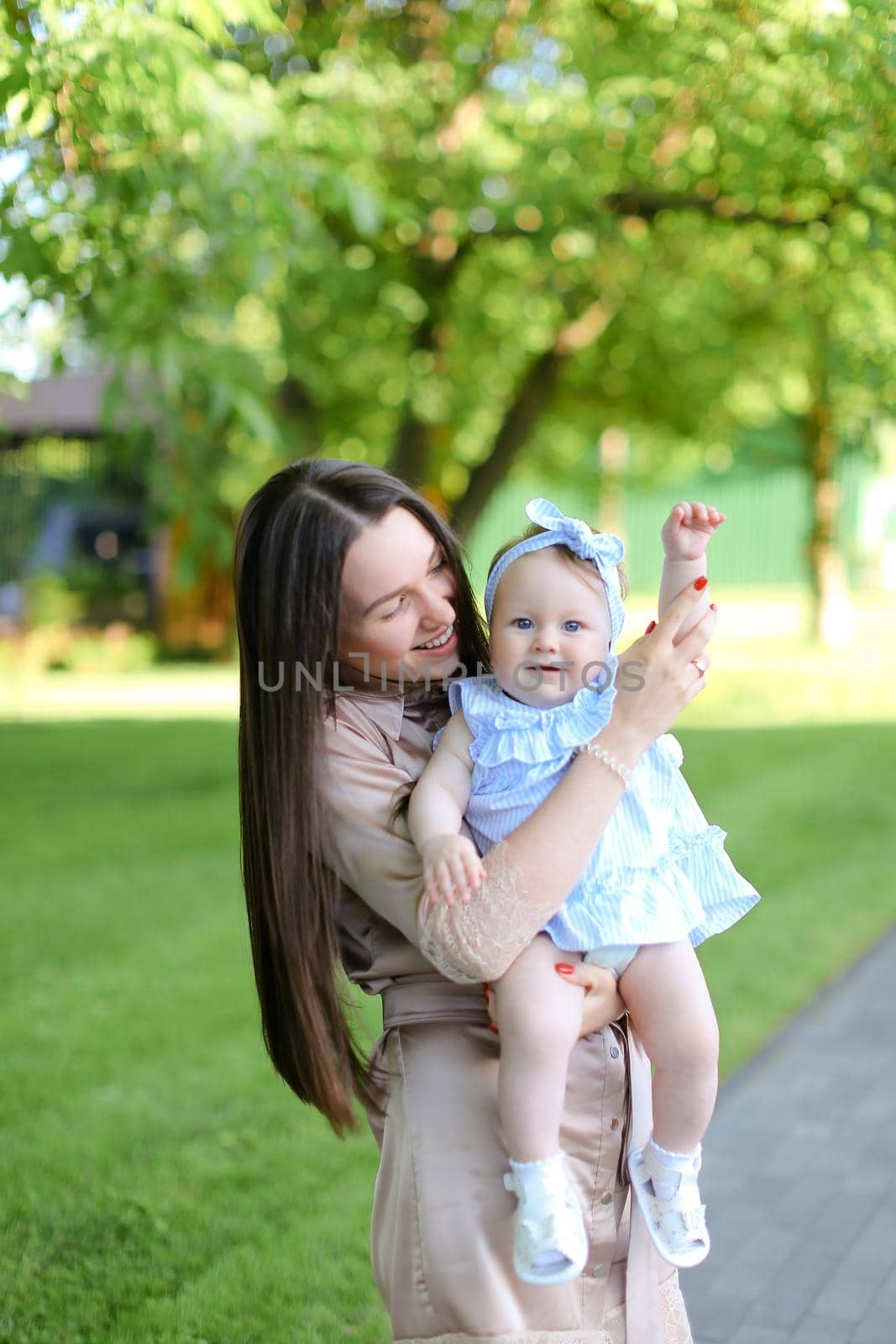 Young caucasian mother holding little female child in garden. Concept of motherhood and resting on nature.