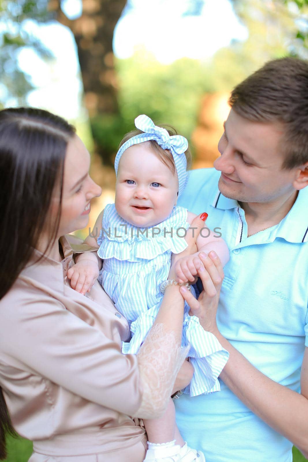 Young gladden mother and father holding little female baby. Concept of parenthood and child.