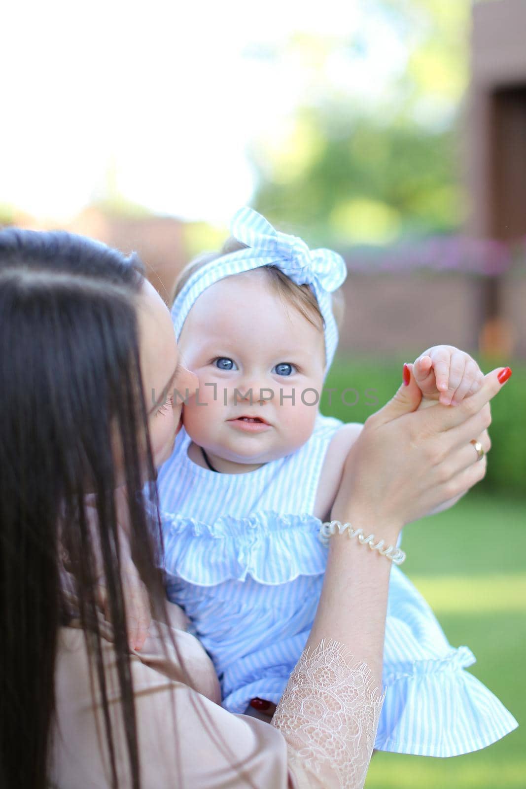 Closeup young aucasian mother holding little female child in blue dress. Concept of motherhood and child.