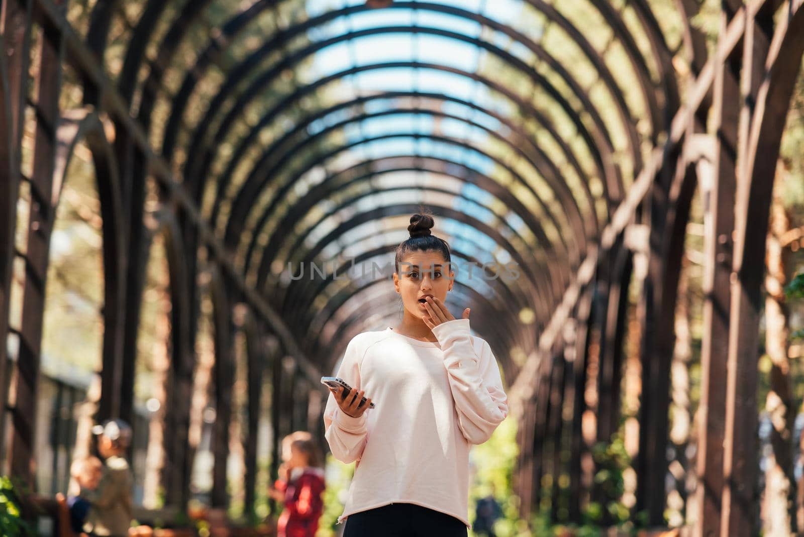 Woman walks along a picturesque alley in summer park.