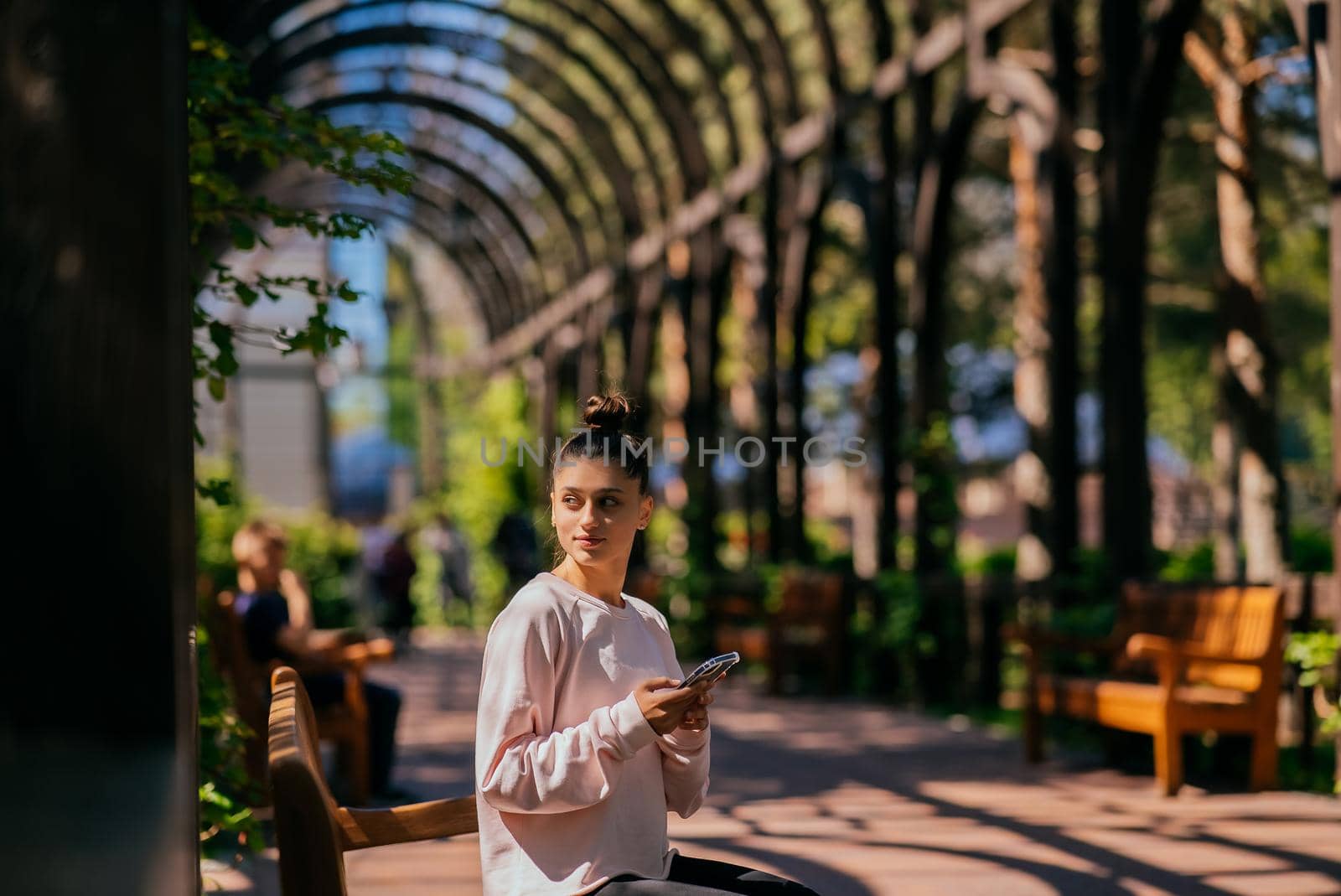 Woman walks along a picturesque alley in summer park.