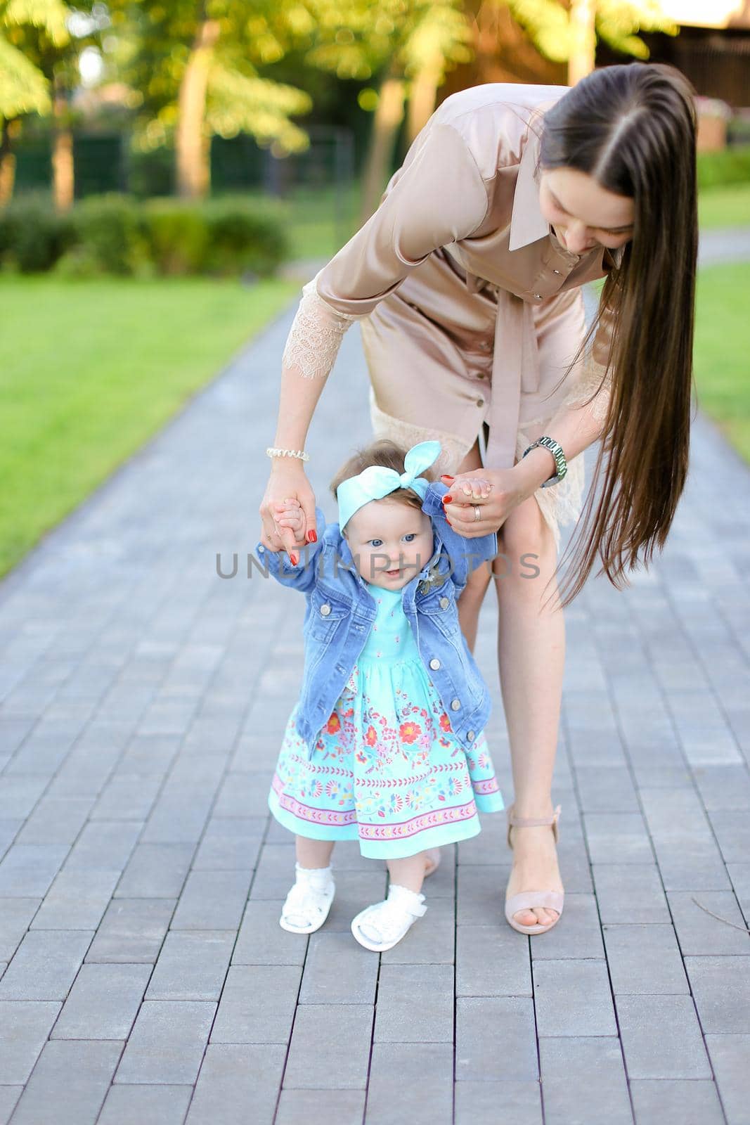 Young mother walking with little daughter in park. Concept of female child and motherhood.