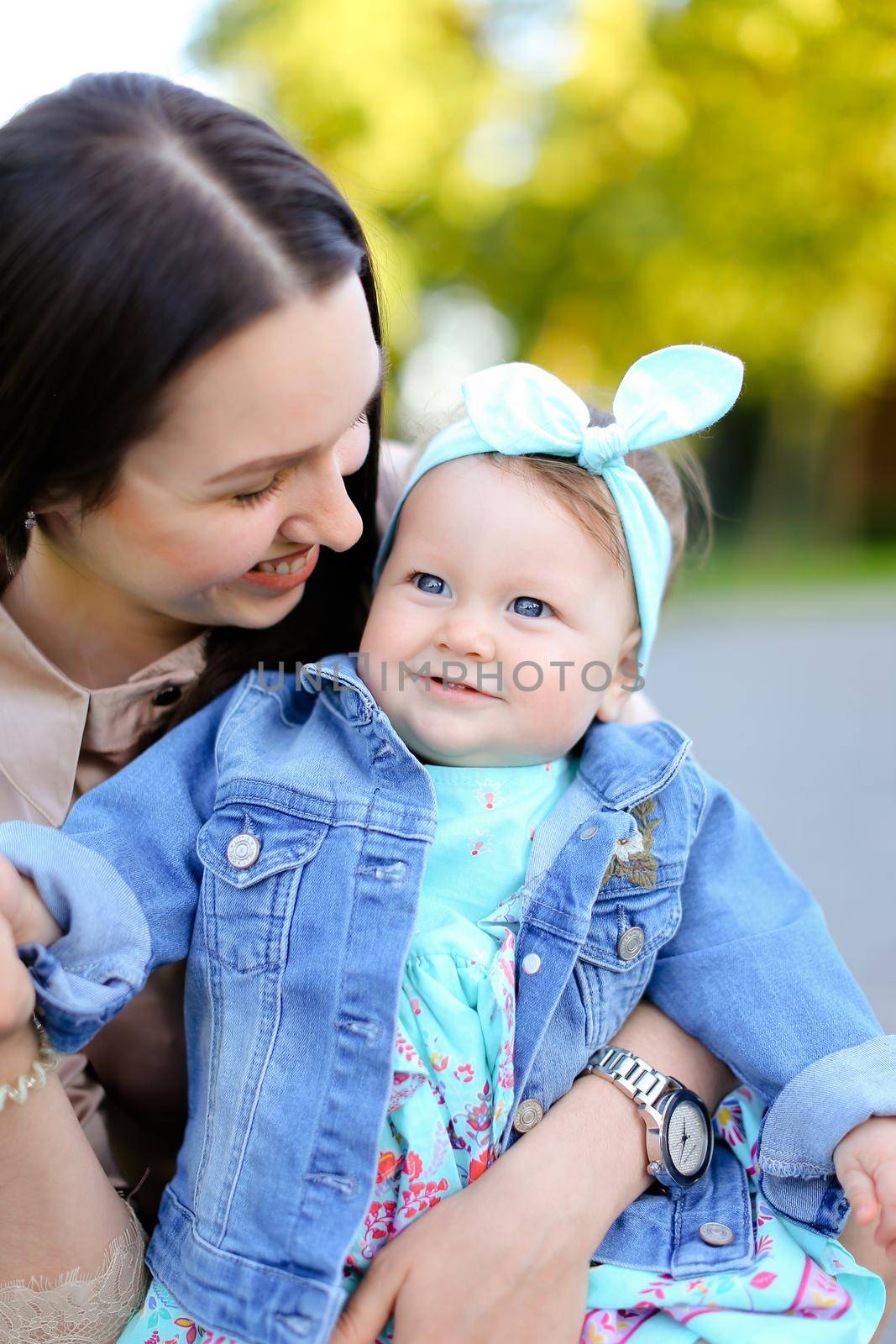 Closeup young gladden mother kissing little daughter wearing jeans jacket. by sisterspro