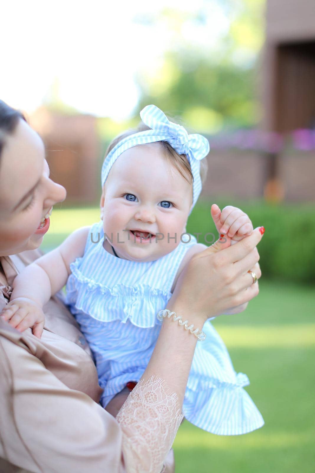 Closeup happy mother holding little female child in blue dress. by sisterspro