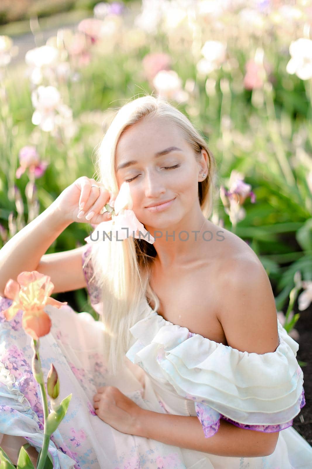 Young smiling woman sitting near irises on garden. by sisterspro