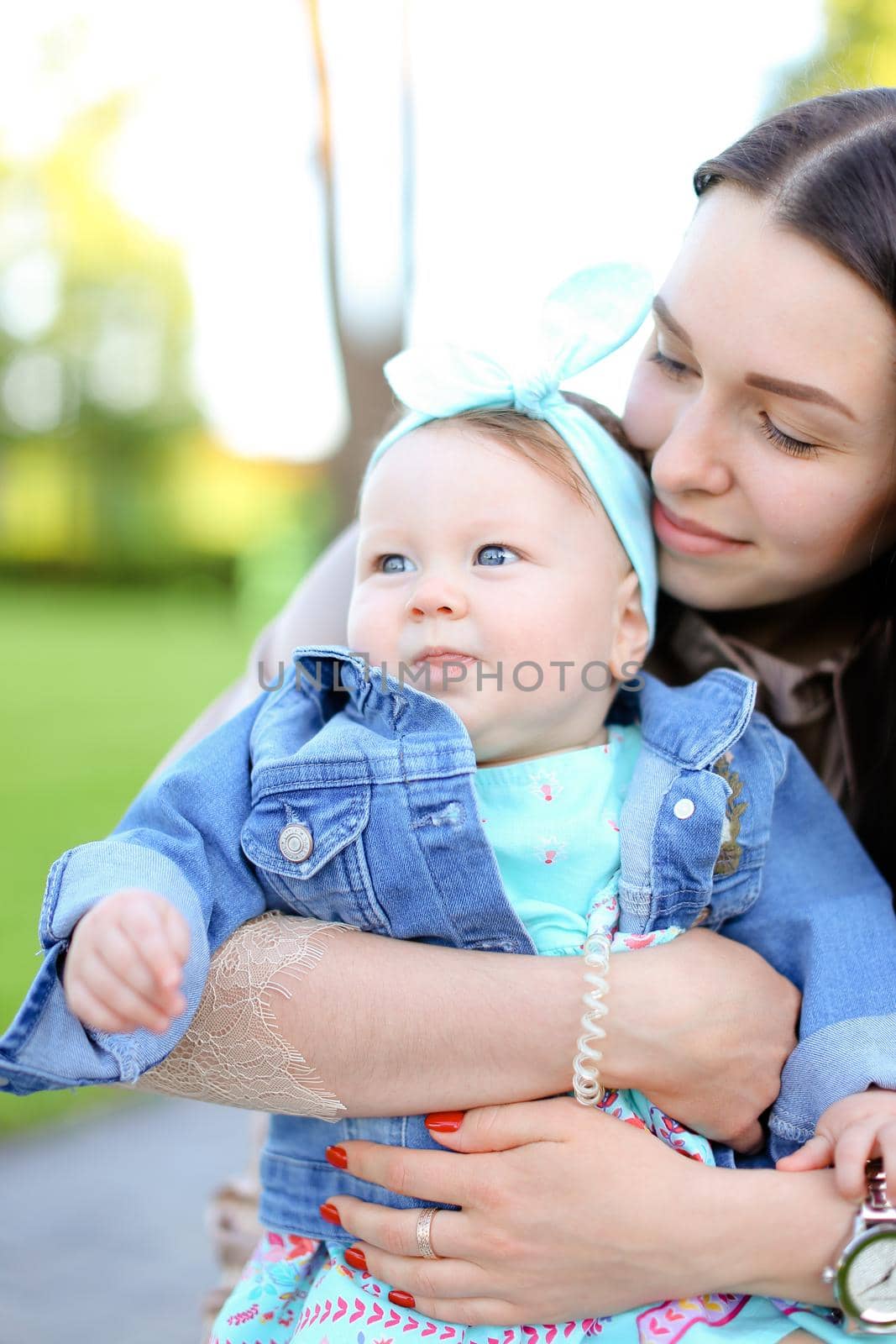 Young happy woman holding little daughter wearing jeans jacket. Concept of motherhood and children.