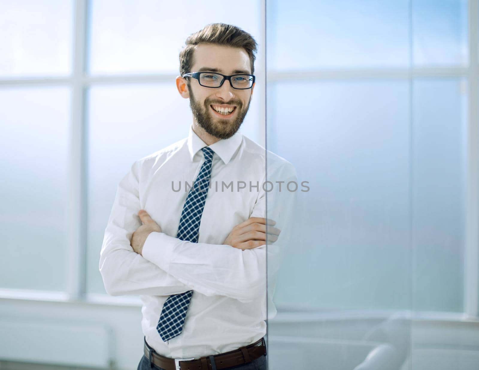 smiling businessman standing near the office window.business people