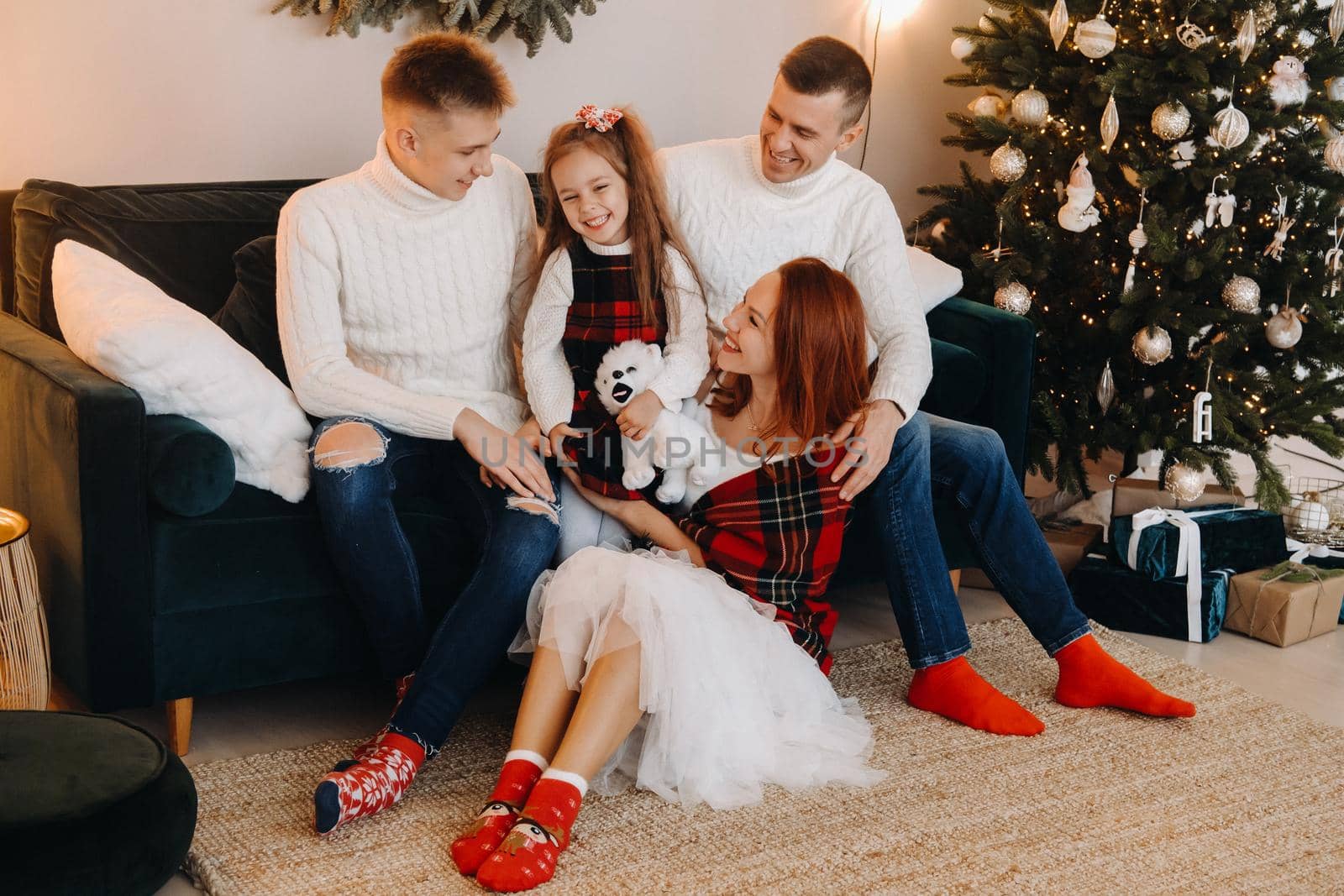 Close-up portrait of a happy family sitting on a sofa near a Christmas tree celebrating a holiday.