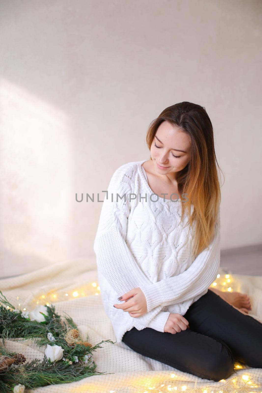 Young girl sitting on bed near wreath and yellow garlands. by sisterspro