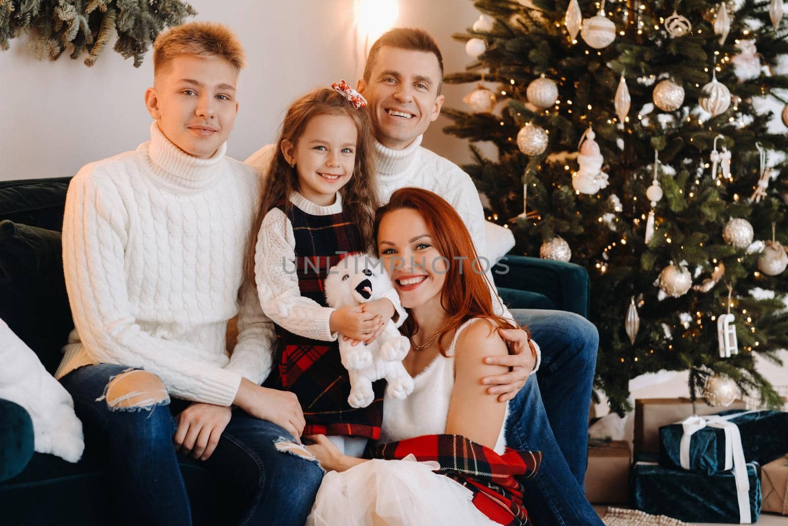 Close-up portrait of a happy family sitting on a sofa near a Christmas tree celebrating a holiday.