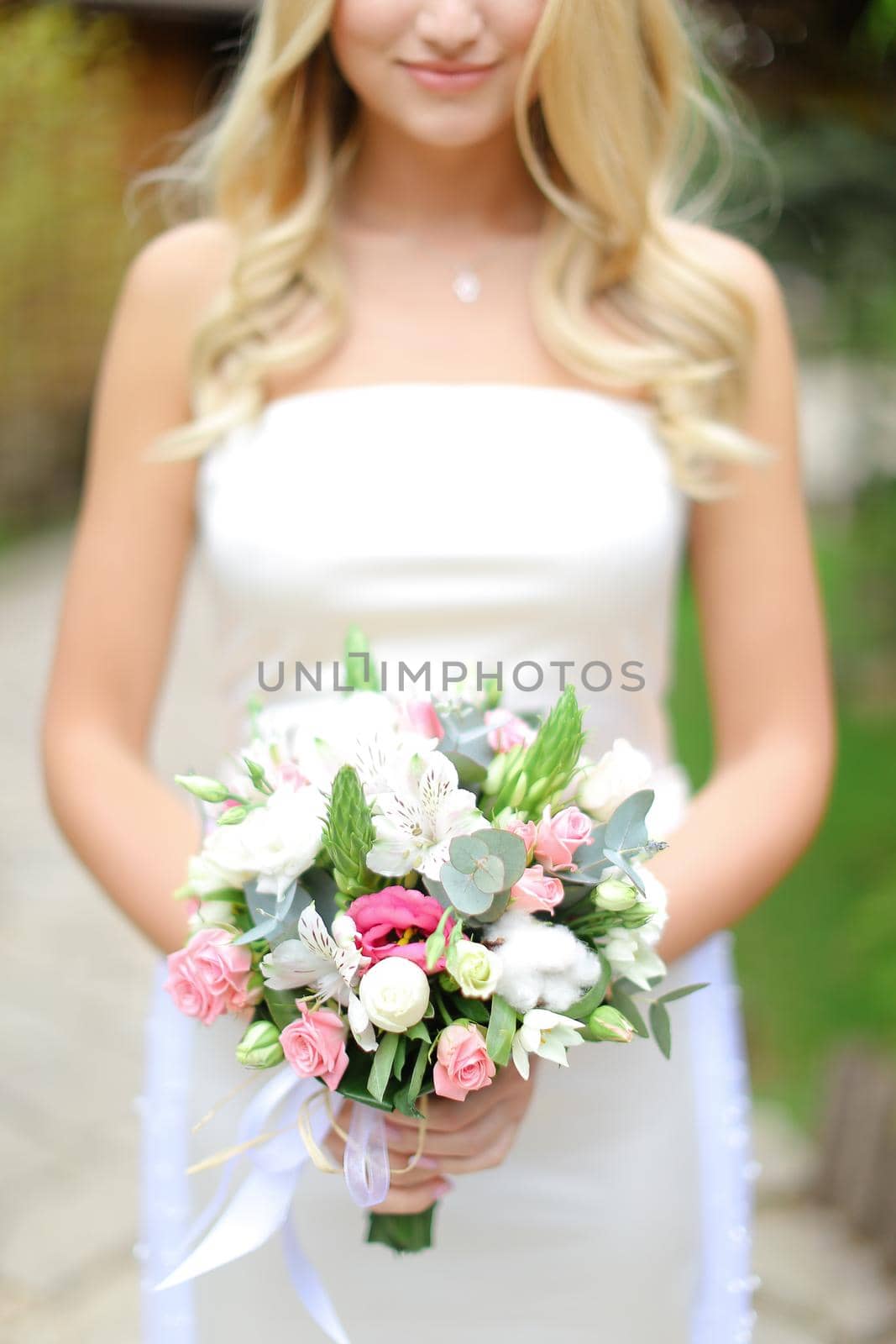 Young blonde bride keeping bouquet of flowers. Concept of wedding and floristic art.