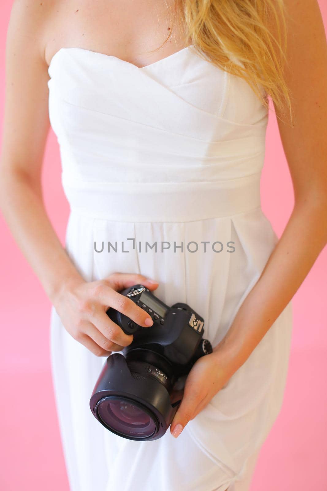 Closeup female photographer with camera in pink monophonic background. by sisterspro