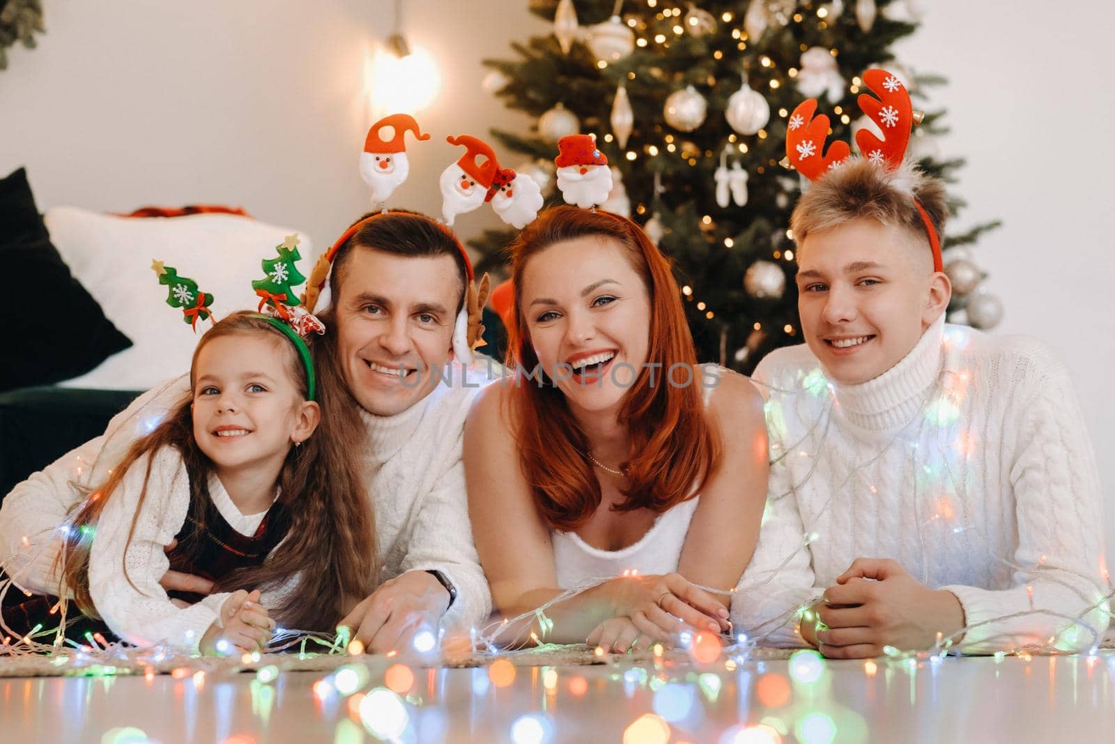 Close-up portrait of a happy family lying near a Christmas tree celebrating a holiday.