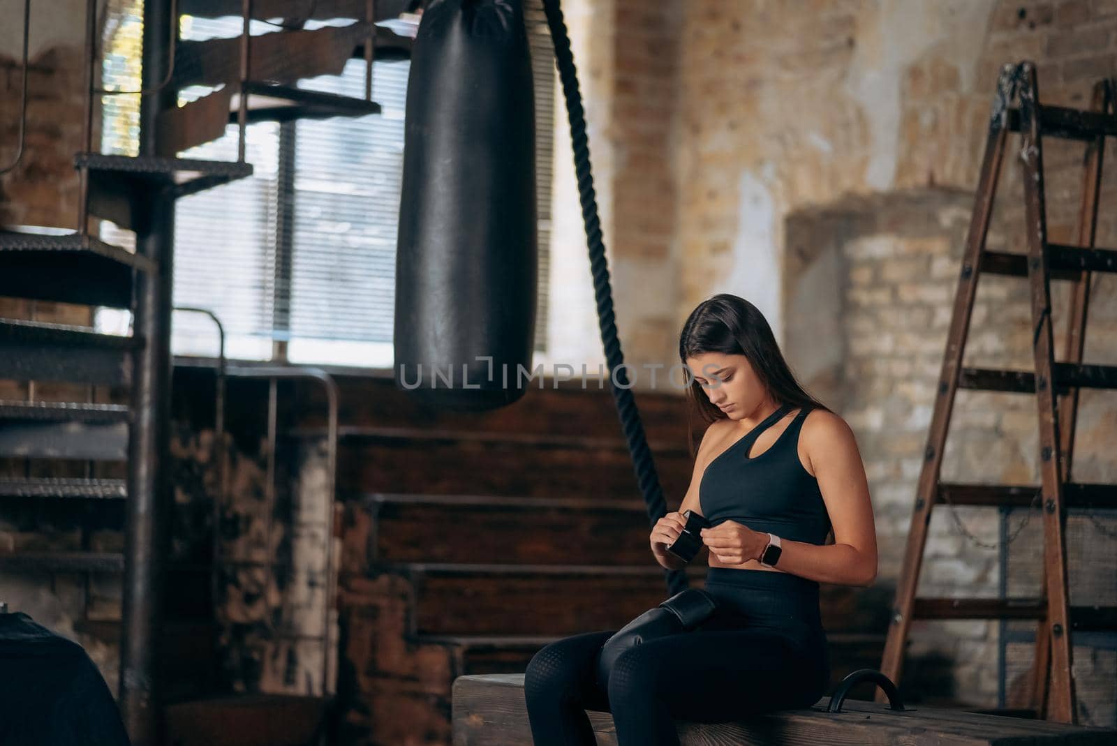 Beautiful confident young fitness girl puts on a boxing glove