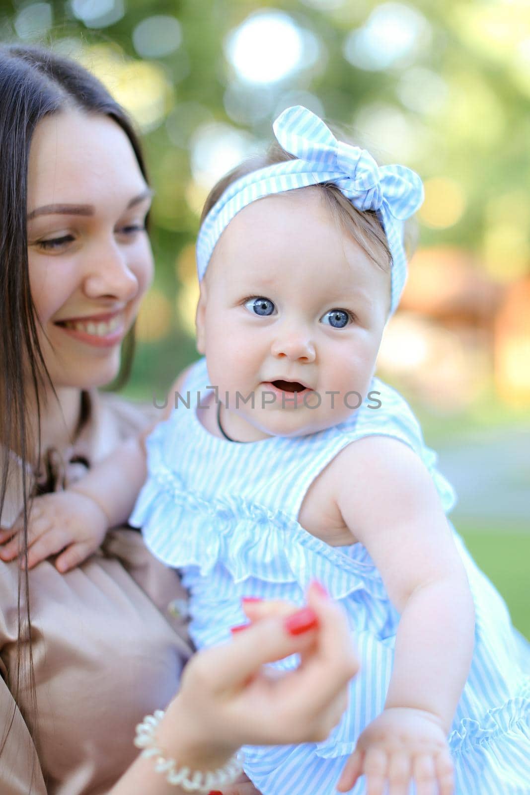 Closeup happy mother holding little female child in blue dress. by sisterspro