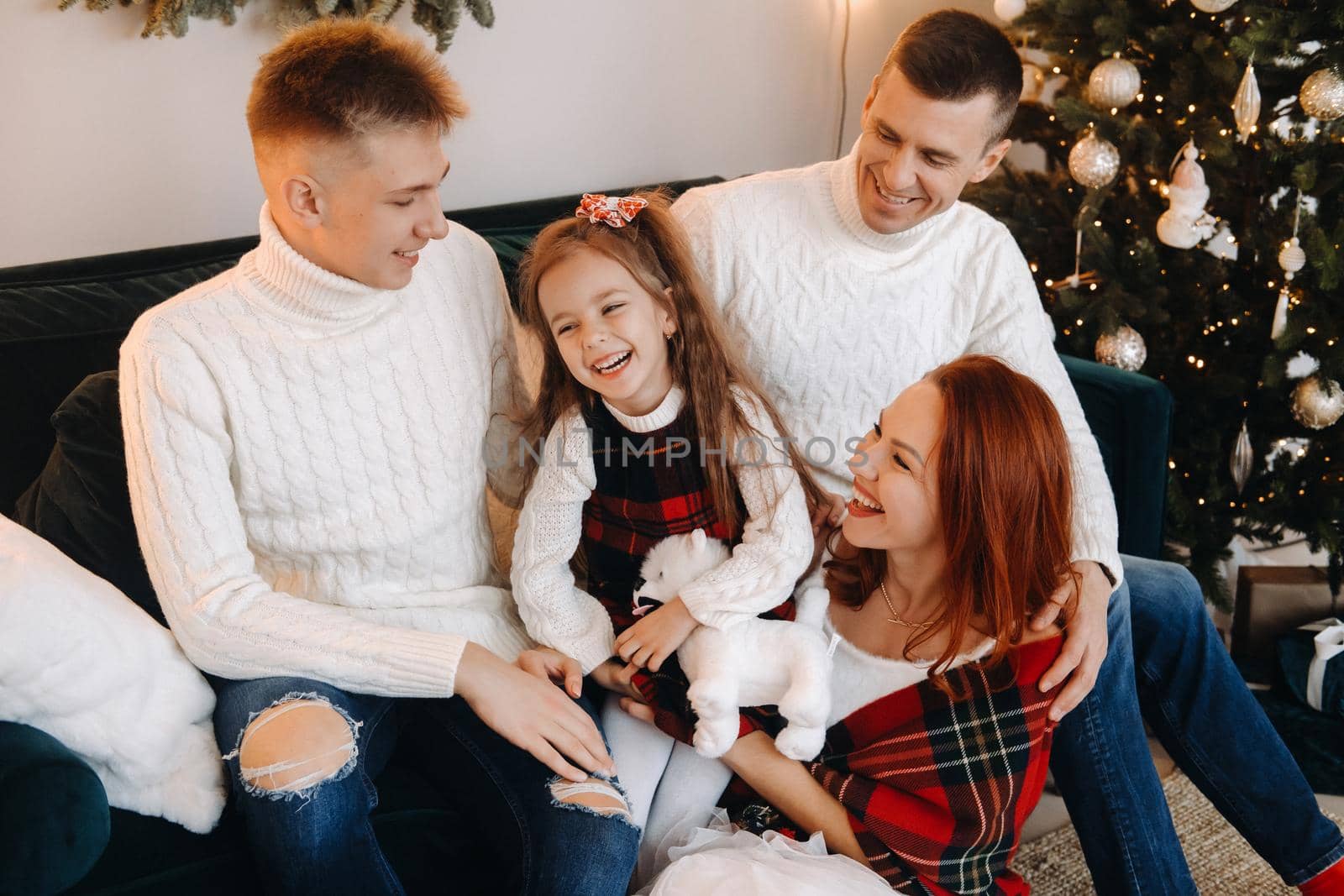 Close-up portrait of a happy family sitting on a sofa near a Christmas tree celebrating a holiday.