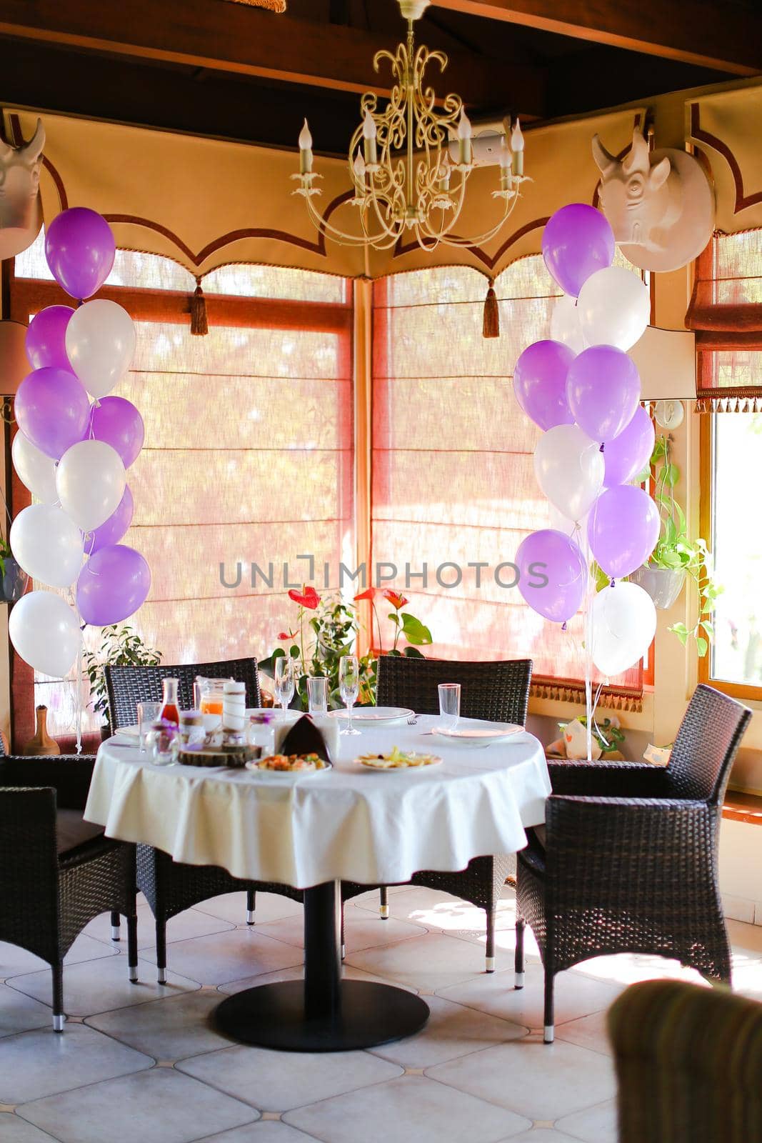 Food on table at cafe and white violet ballons. Concept of preparations for birthday.