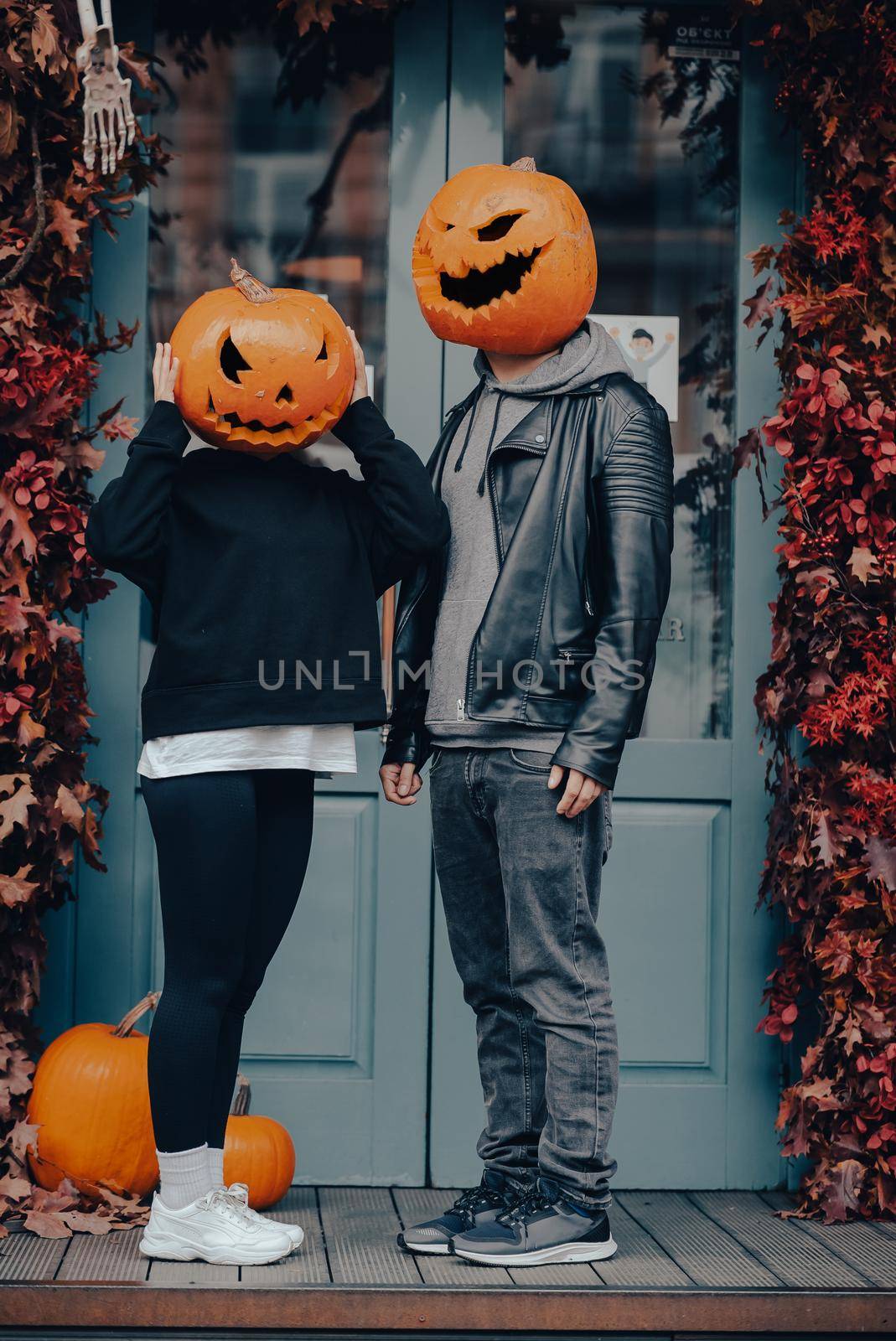 Couple with pumpkin heads posing on camu at the entrance to the building . Halloween Concept