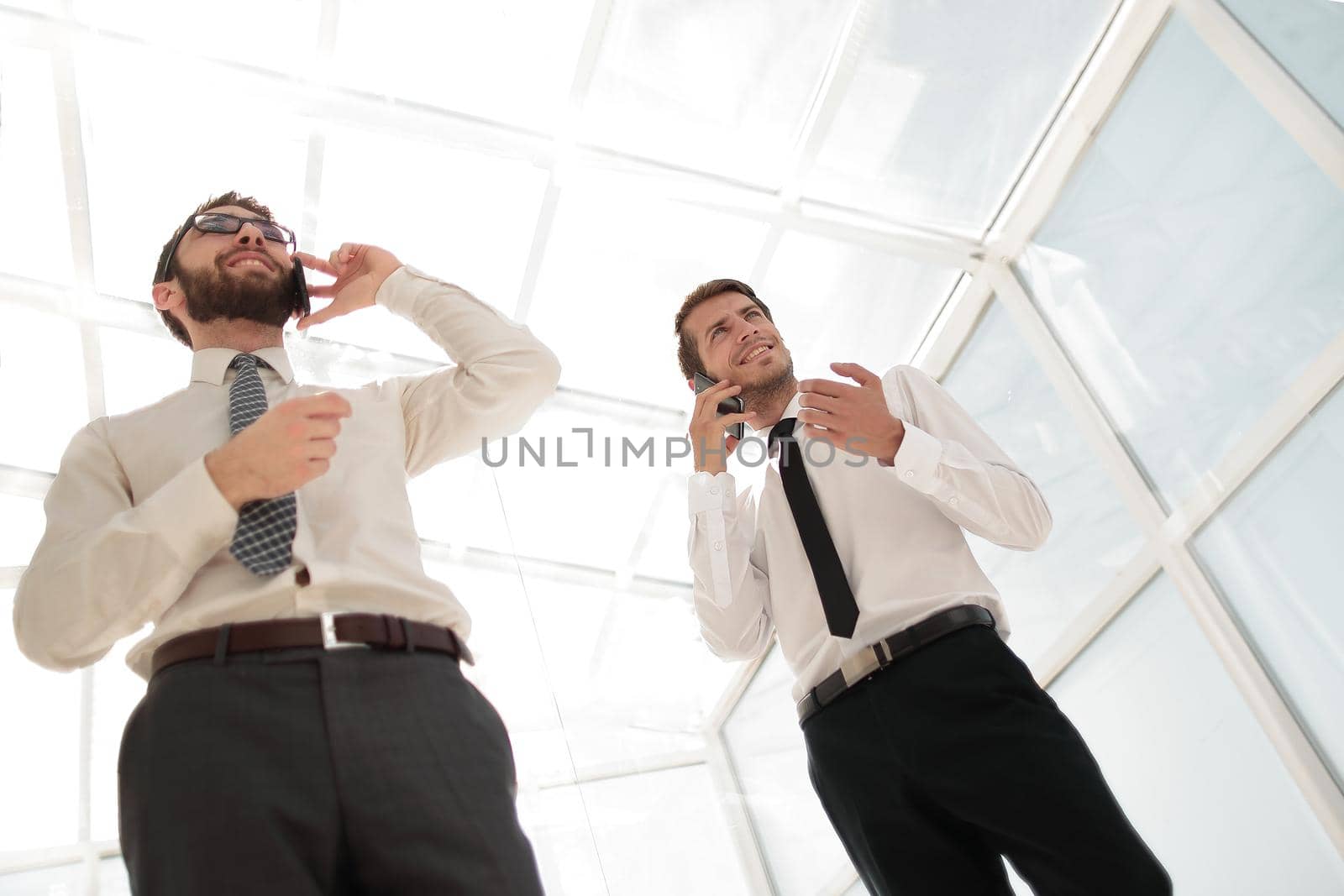bottom view.two successful businessmen talking on their smartphones.business concept
