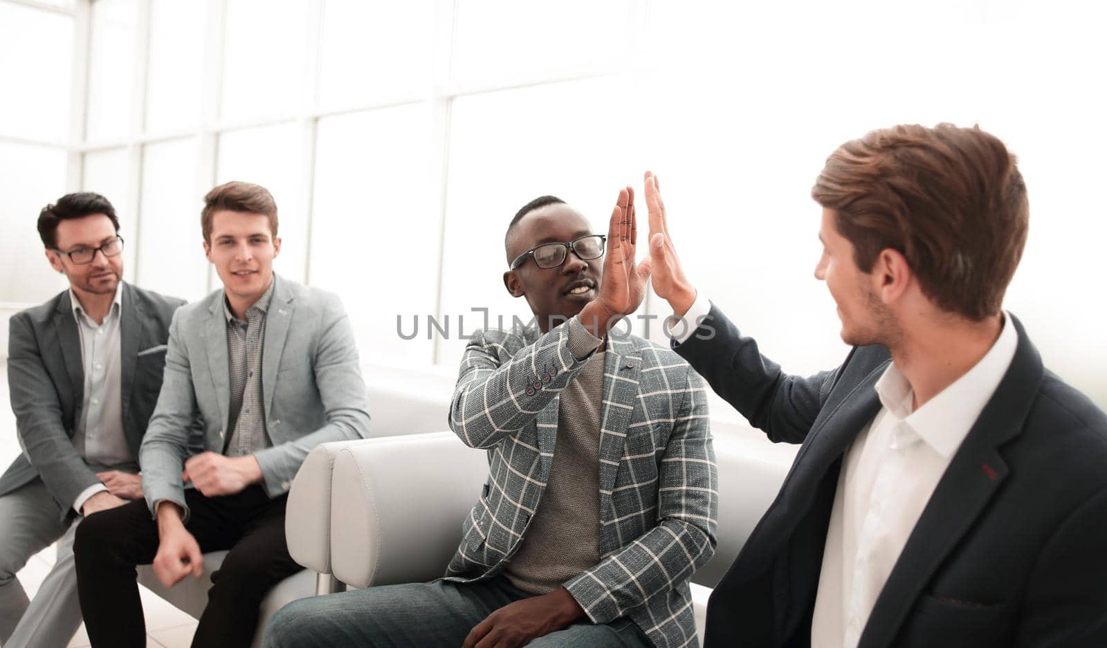 business colleagues giving each other a high five while sitting in the office lobby.photo with copy space