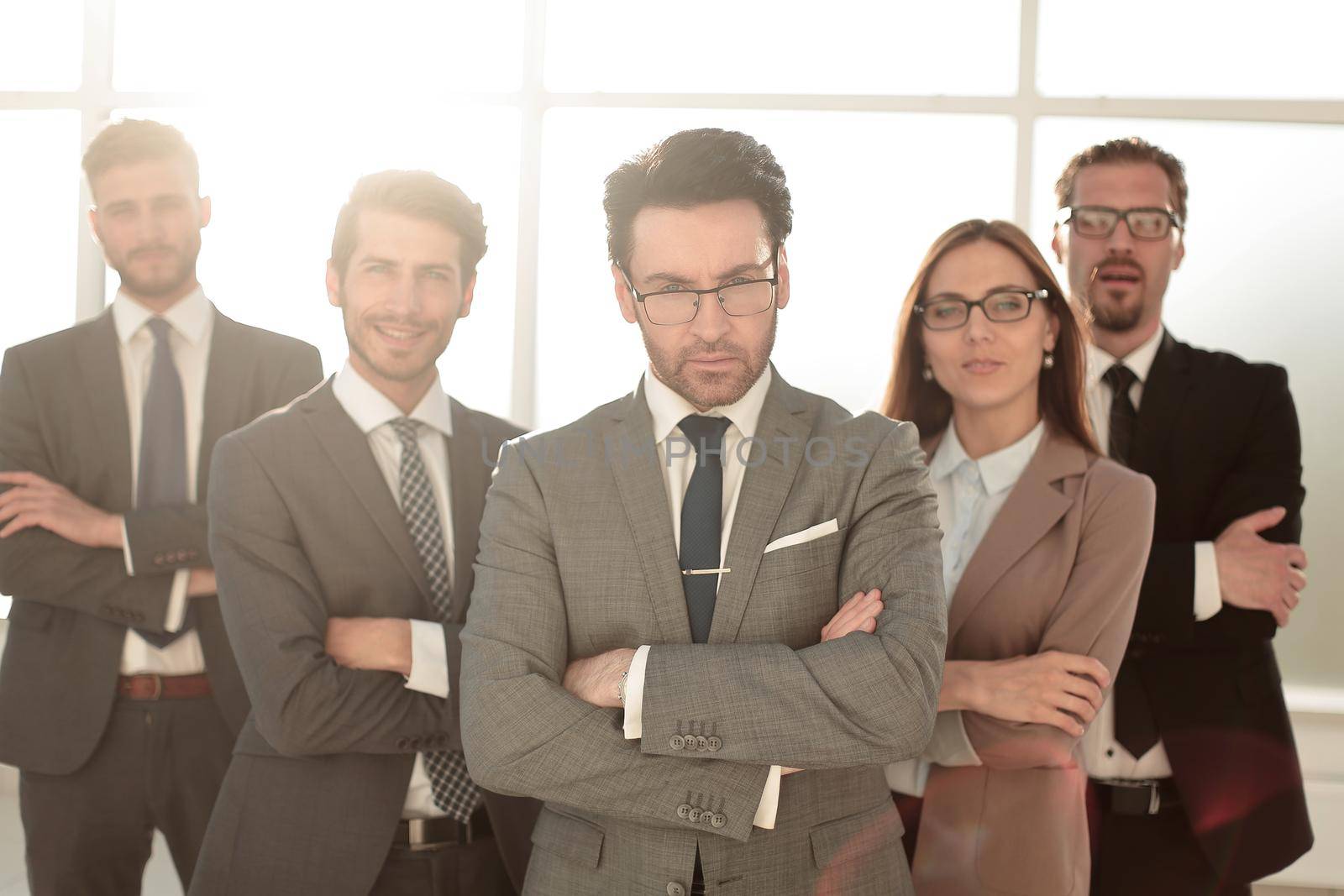 Smiling and confident business team standing in front of a bright window