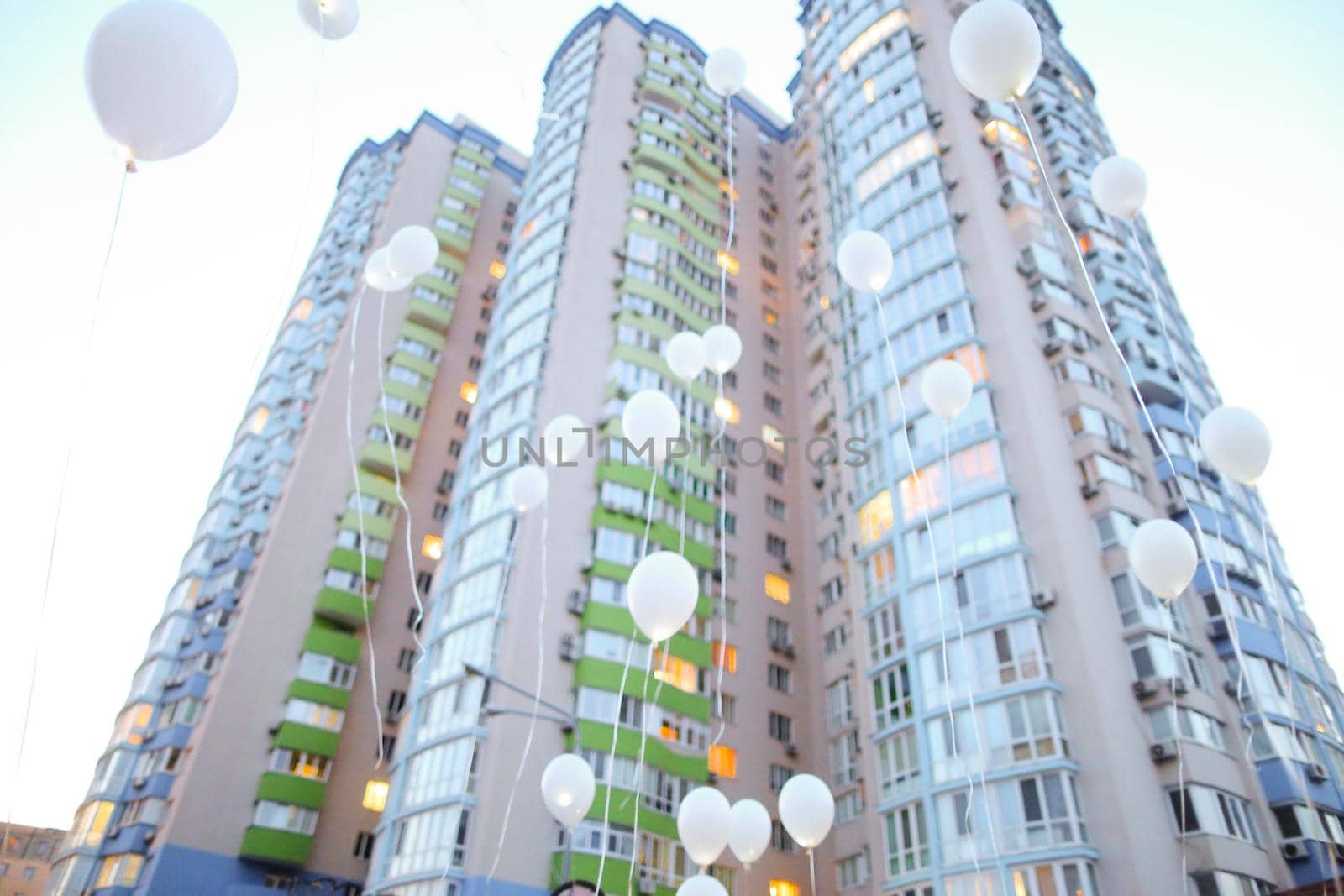 High building and flying white balloons. Concept of celebrating success.