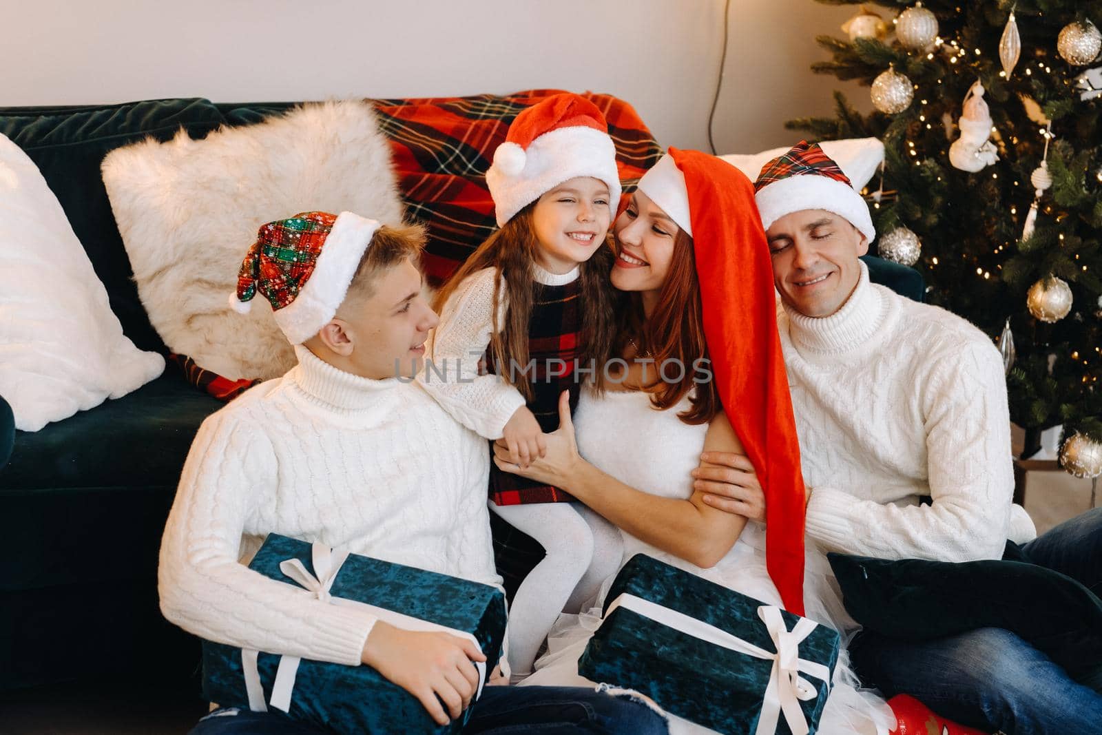 Close-up portrait of a happy family sitting on a sofa near a Christmas tree celebrating a holiday.