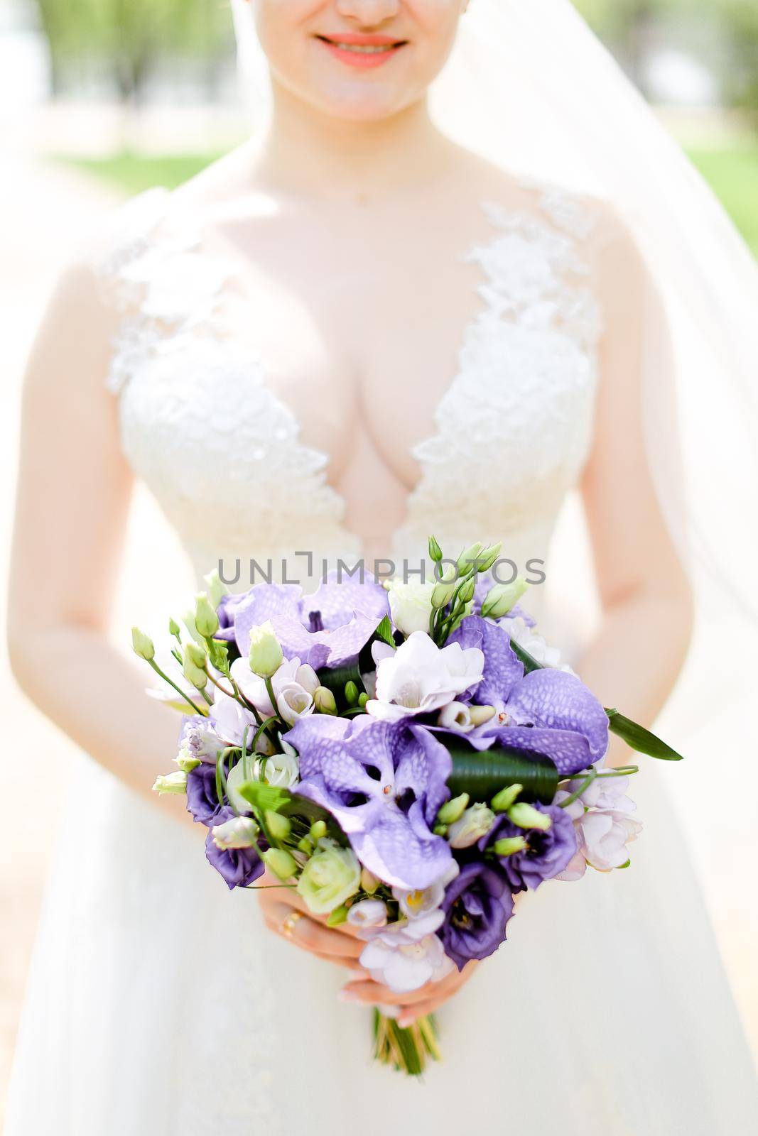 aucasian happy bride keeping bouquet of flowers and wearing white dress with veil. by sisterspro