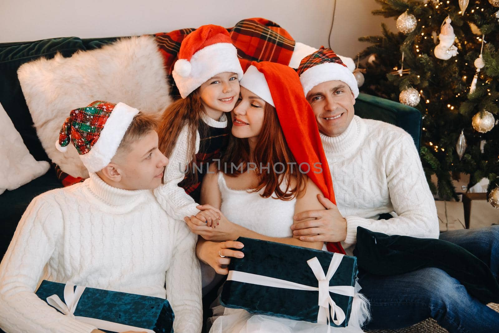 Close-up portrait of a happy family sitting on a sofa near a Christmas tree celebrating a holiday.