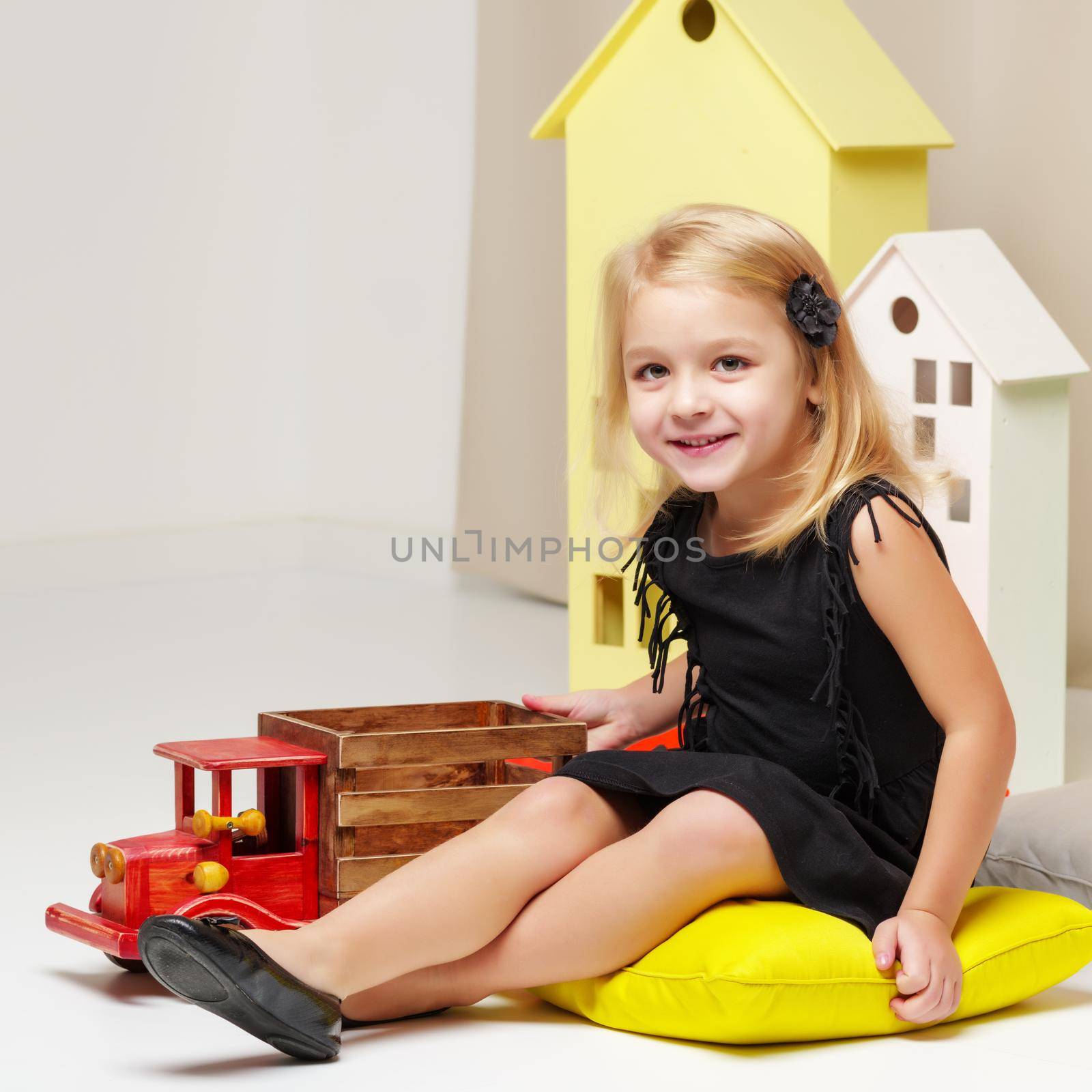 Little girl is playing with a wooden car. by kolesnikov_studio