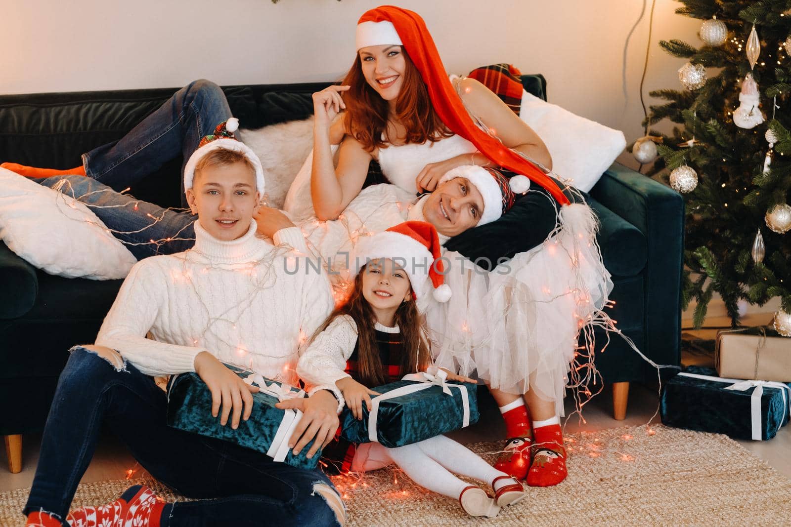 Close-up portrait of a happy family sitting on a sofa near a Christmas tree celebrating a holiday.