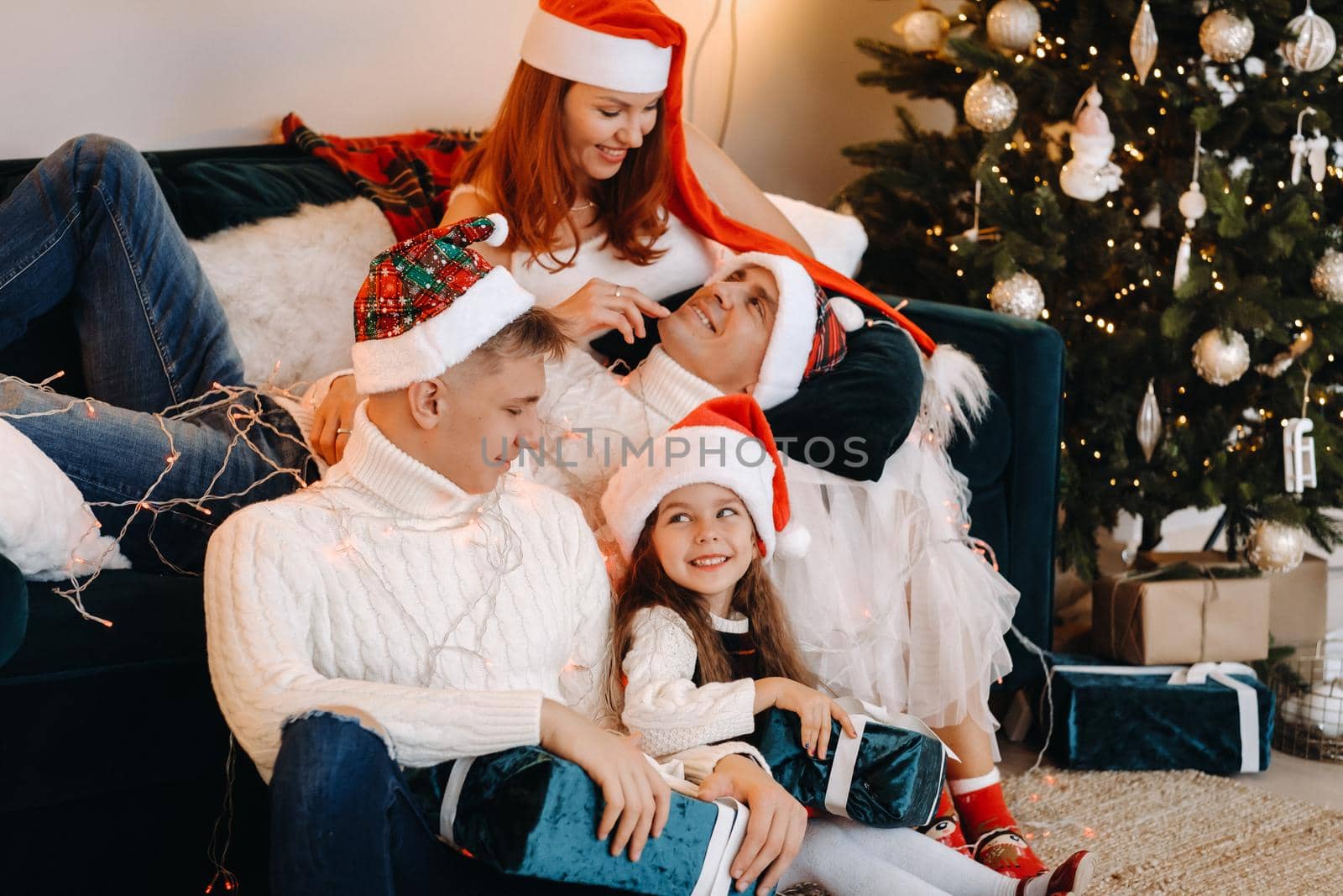 Close-up portrait of a happy family sitting on a sofa near a Christmas tree celebrating a holiday.