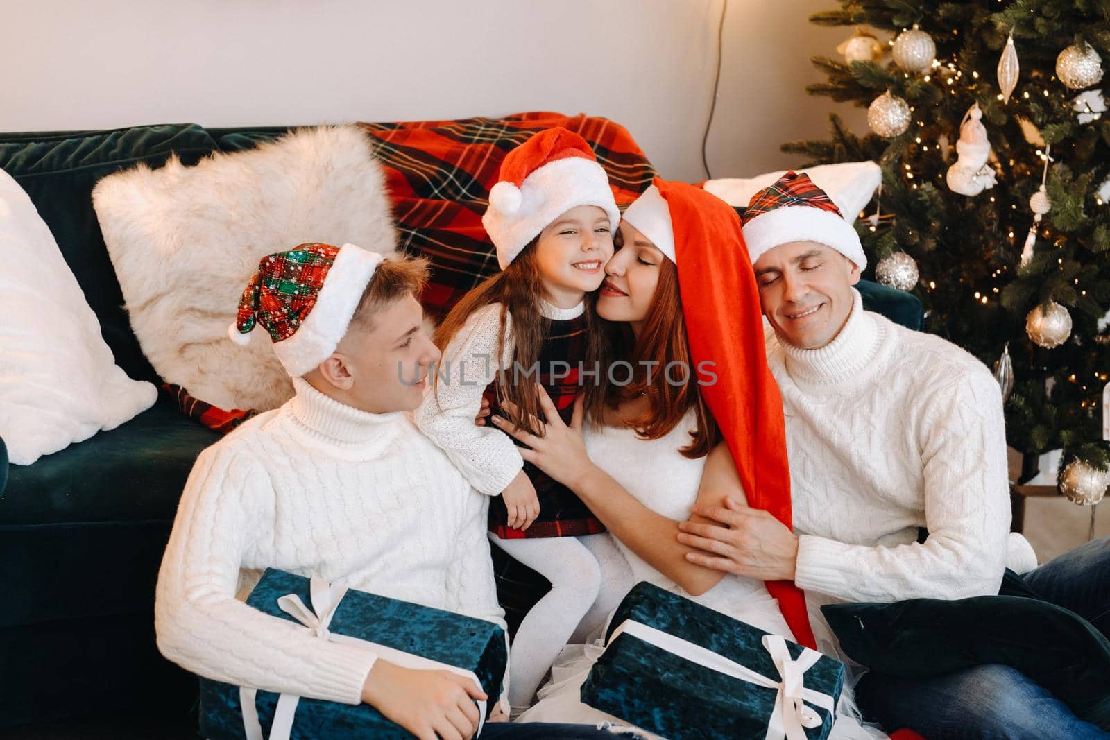 Close-up portrait of a happy family sitting on a sofa near a Christmas tree celebrating a holiday.