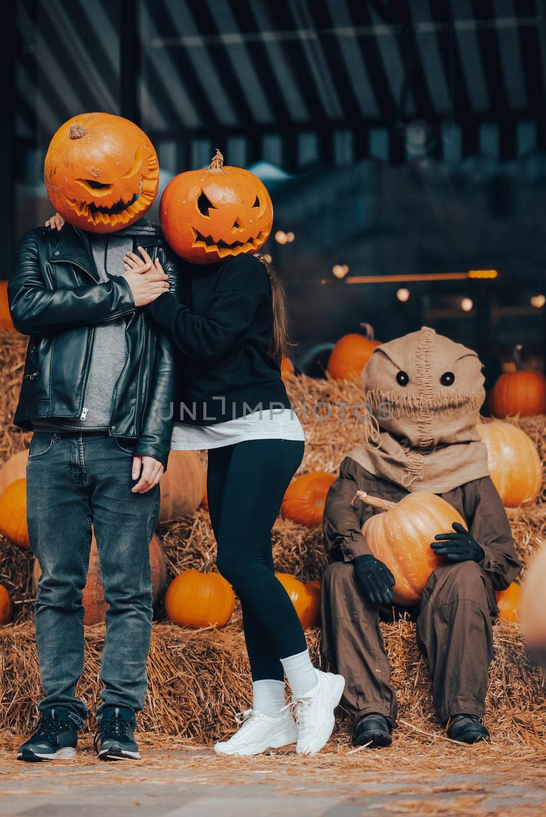 A guy and a girl with a pumpkin heads posing at the scarecrow. Halloween Concept