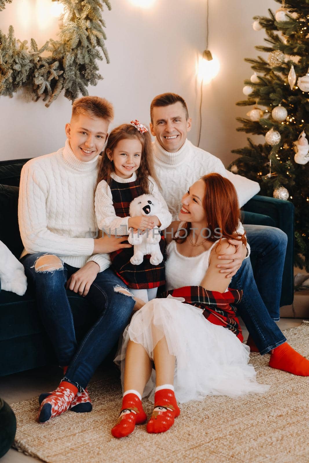 Close-up portrait of a happy family sitting on a sofa near a Christmas tree celebrating a holiday.